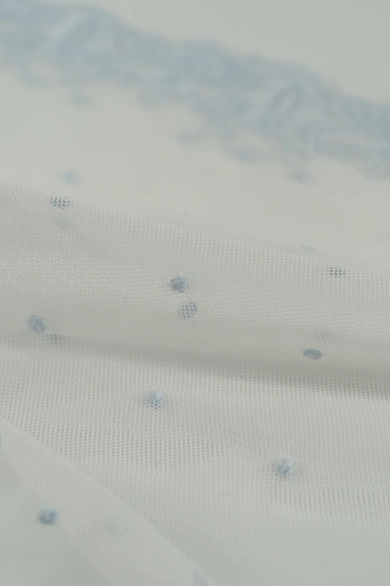 Tule bordado com plumeti azul claro e rebordo pequeno.