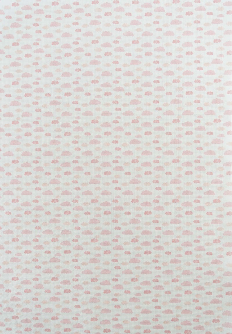 Tejido infantil con estampado de nubes rosas. 