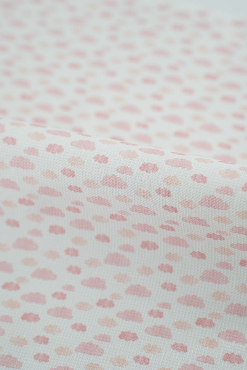 Tejido infantil con estampado de nubes rosas. 